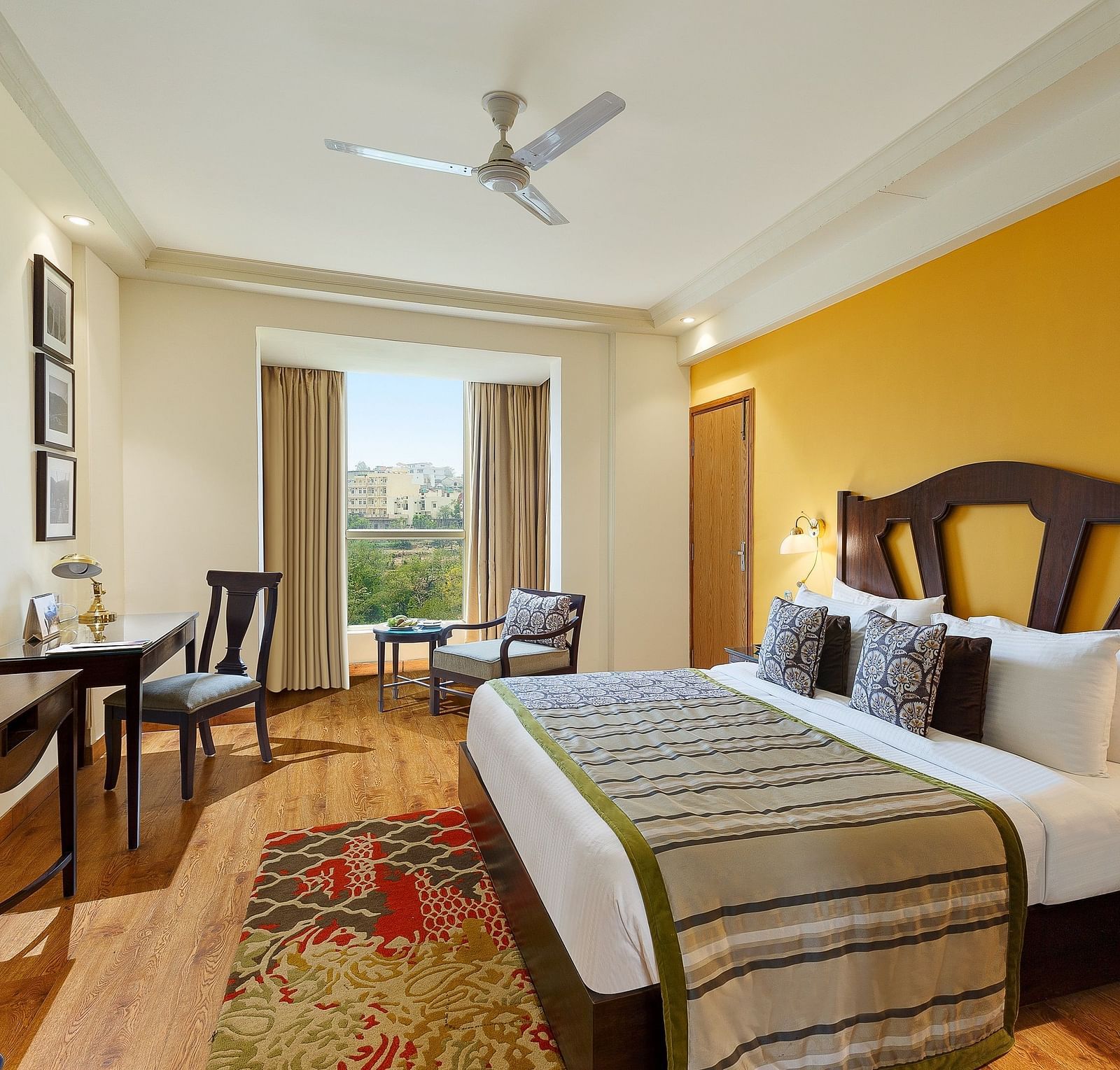 An image of the room features a king-size bed with a plush headboard and comfortable bedding. A comfortable armchair sits by the window, offering a view of the outdoors. 