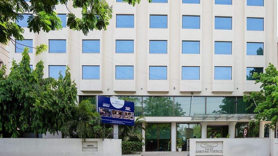  A facade image of the Marasa Sarovar Portico, Rajkot with trees around.