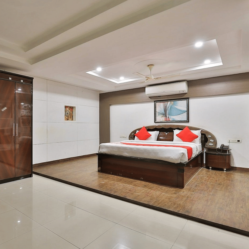 An overview of the Premium Suite with a king bed, a wall mounted AC, side tables and a large wardrobe in view at VITS Select, Bharuch.