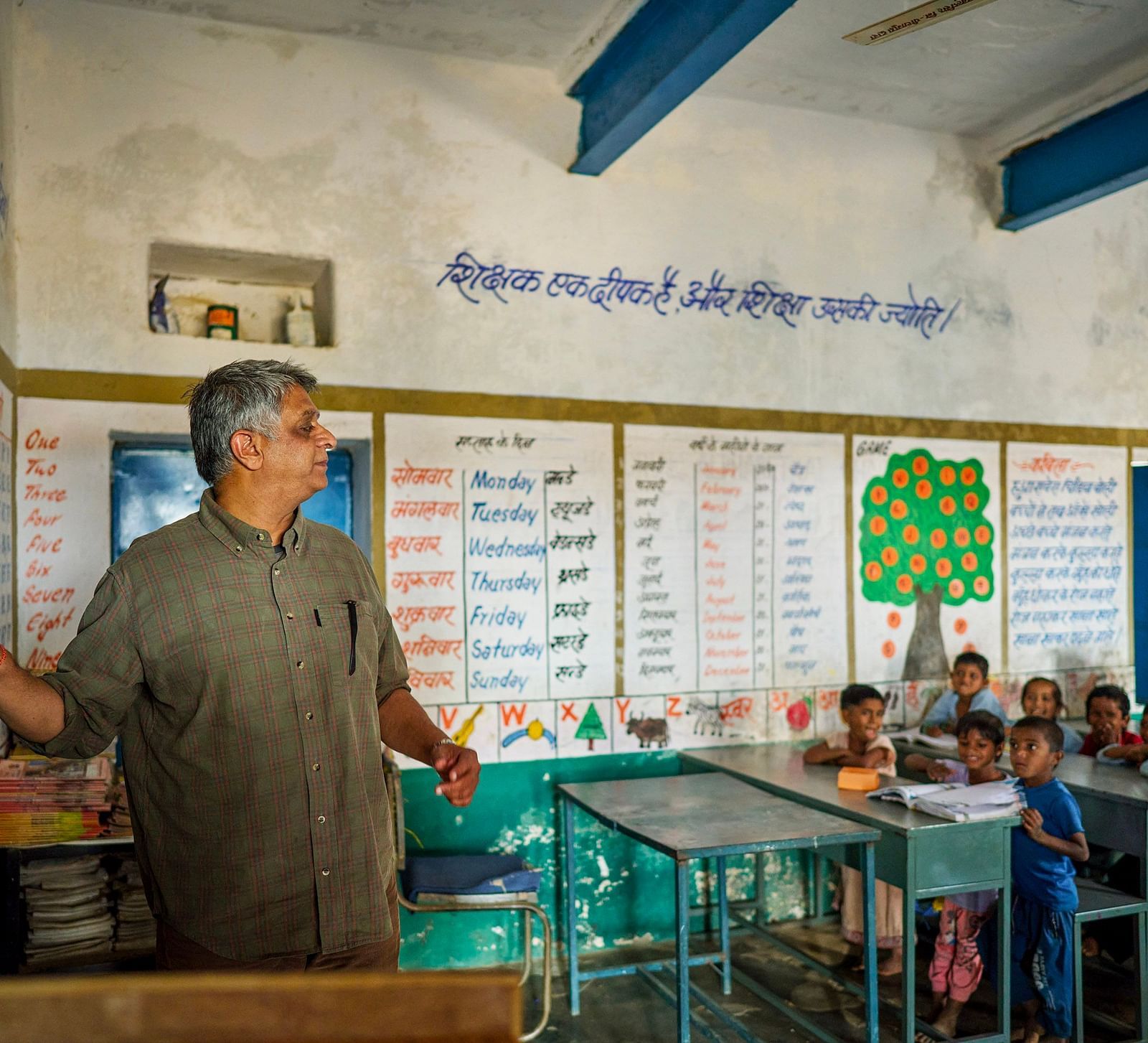 image of an old man teaching with the help of a chalk and blackboard to the students