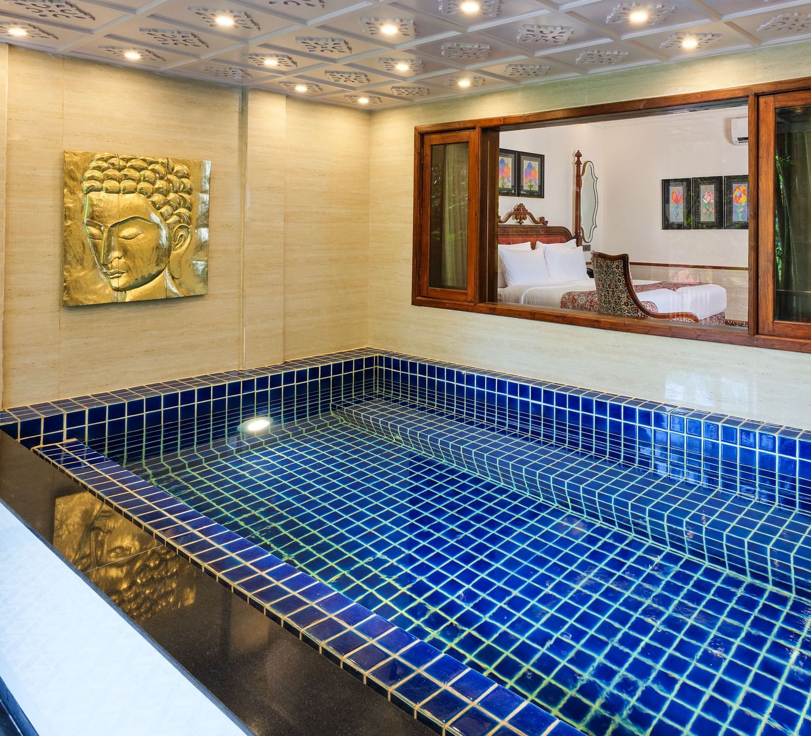 Royal Villa private swimming pool with a gold artwork on the wall. a window through which the bedroom can be seen.