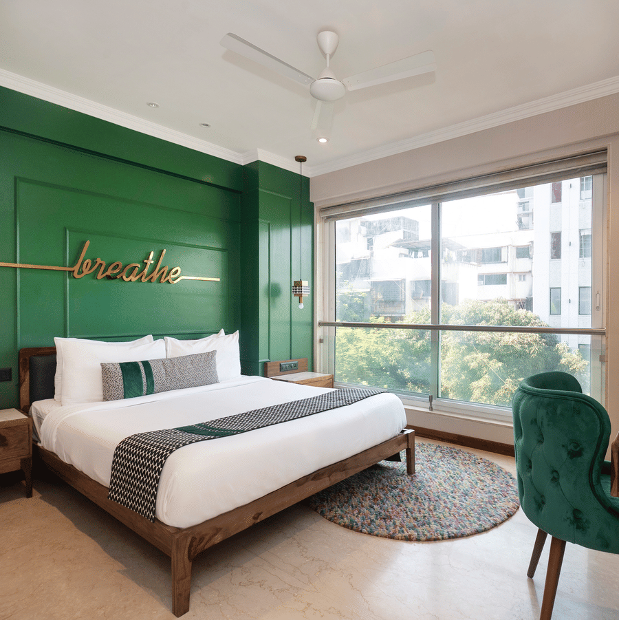 Deluxe Room featuring a plush bed facing the wall-mounted TV with a work desk below, offering a serene stay in Bandra at Theory9 - Premium Service Apartments