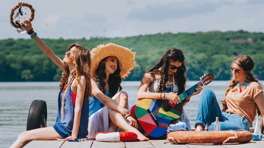 a group of women sun bathing and one girl playing the guitar with the backdrop of a lake - Caravela Beach Resort, Goa