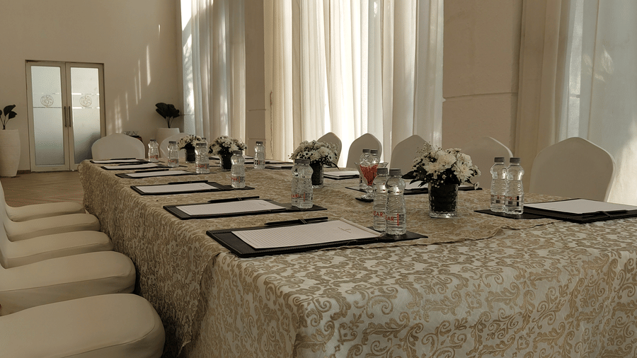 The Mansion House resort meeting setup with long rectangular table, beige tablecloth, white-covered chairs, notepads, and floral arrangements, designed for conferences or formal gatherings.