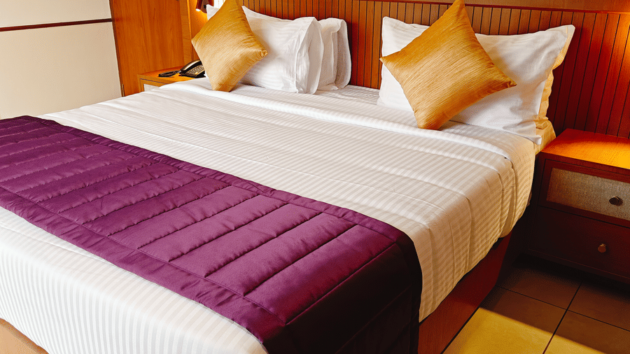 A neatly made king bed at Bliss Giriya By Bergamont Tiruvannamalai with a wooden headboard and cushioned pillows.