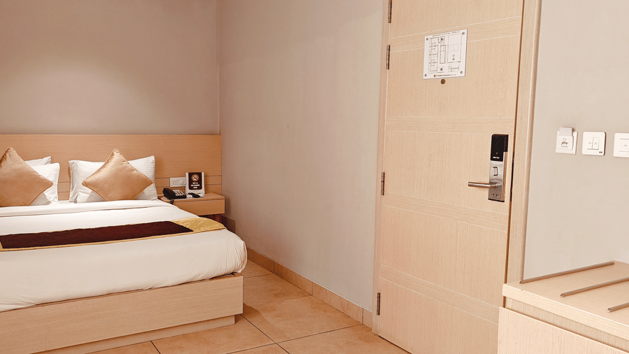 Side view of the Business Class Room bed at Chola Dynasty, Kumbakonam highlighting the minimalist décor, soft lighting, comfortable mattress, and peaceful ambience suited for a relaxing stay.