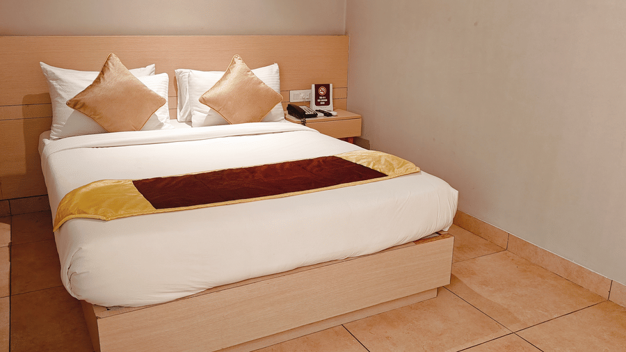 Front view of the comfortable bed in the Deluxe Single Room at Chola Dynasty, Kumbakonam showcasing plush bedding, soft pillows, warm tones, and a cosy interior designed for restful nights.