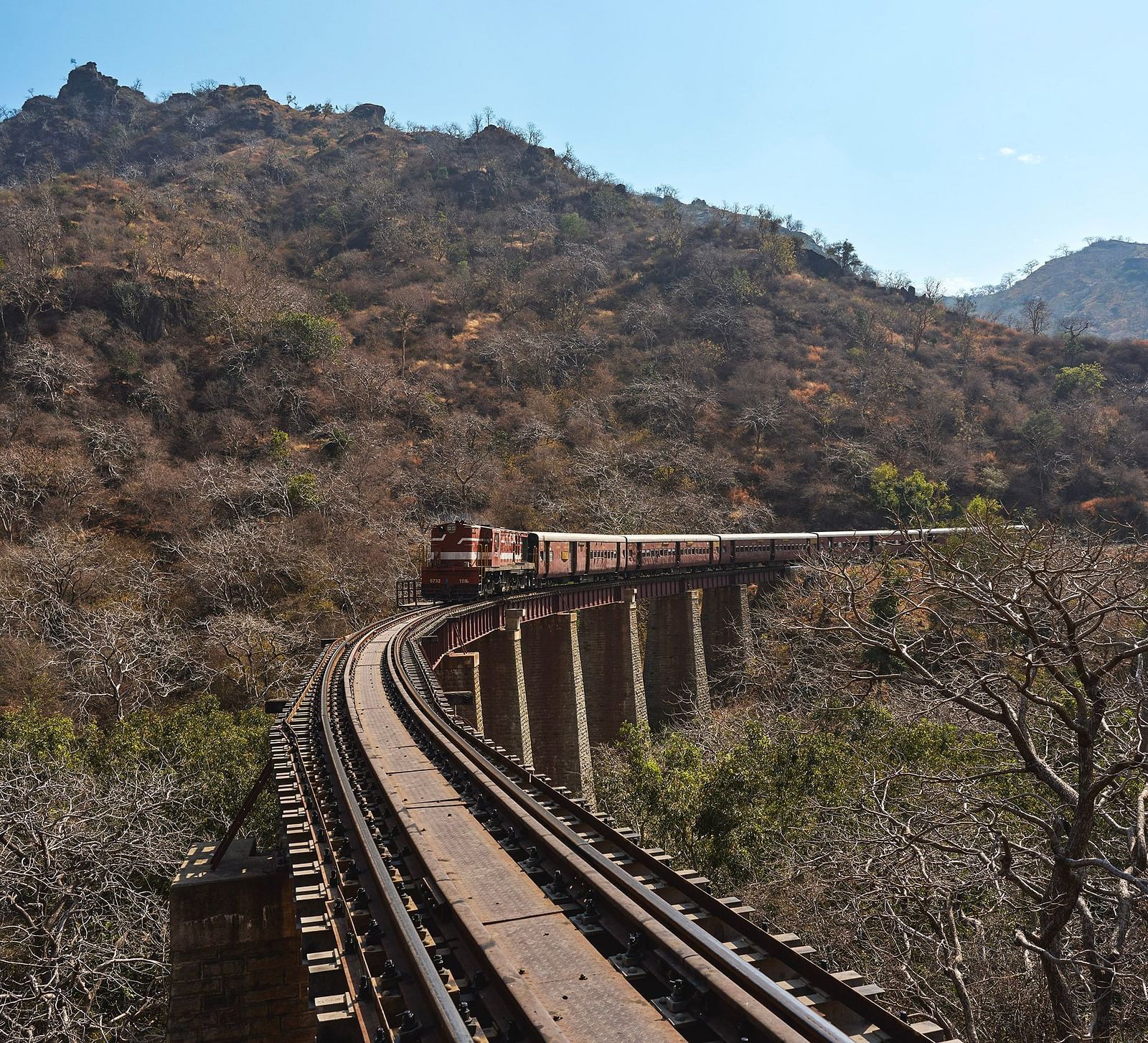 image of a train approaching over a bridge with mountain hills in the background