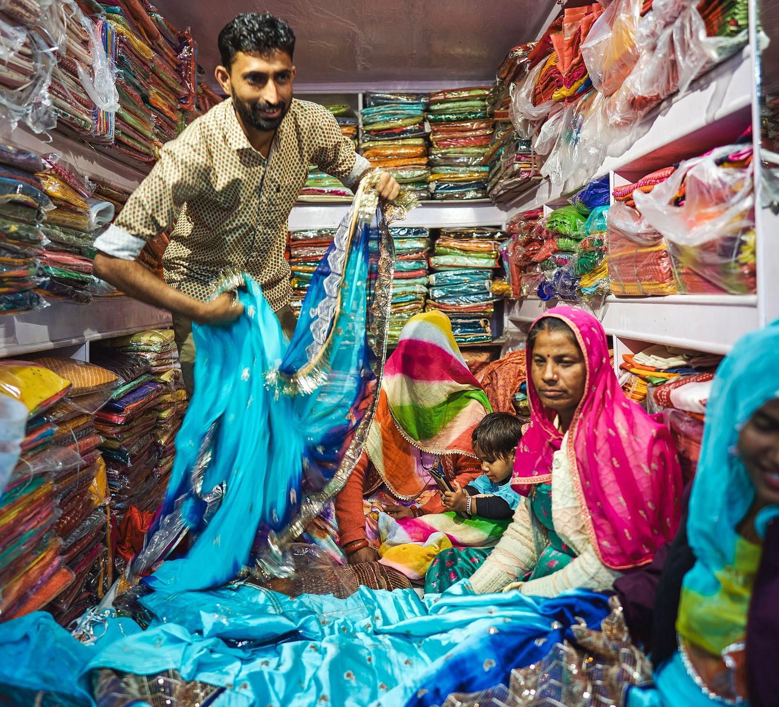 image of a man selling traditional rajasthani sarees in a shop to local women