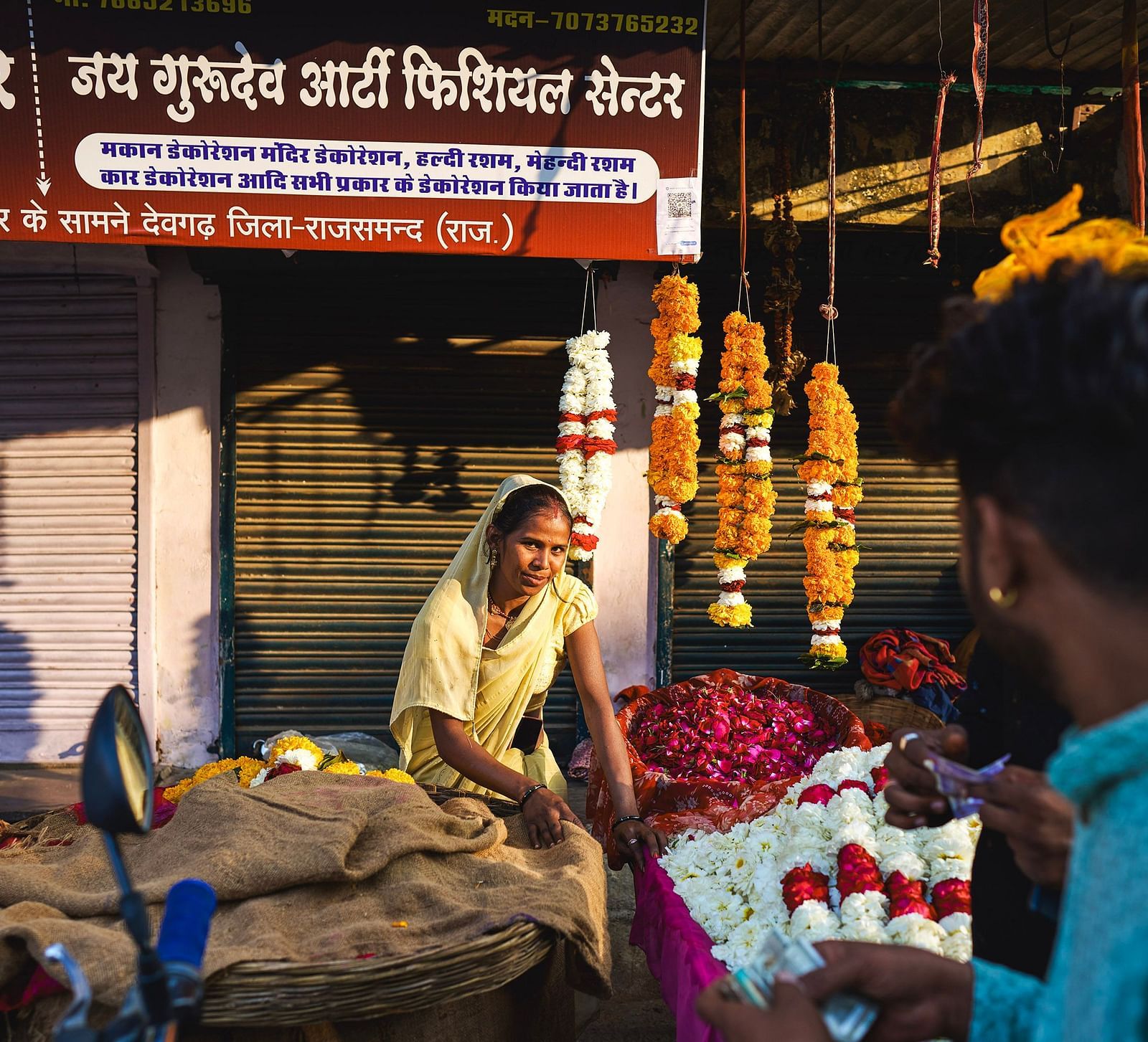 image featuring a woman flower vendor selling various flowers and garlands in a market