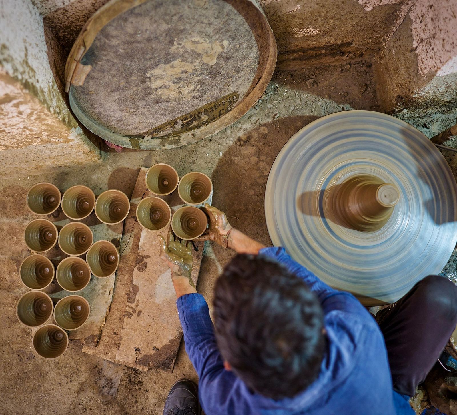 image of a person engaged in pottery where he places the freshly made clay pot on a platform with the other pots