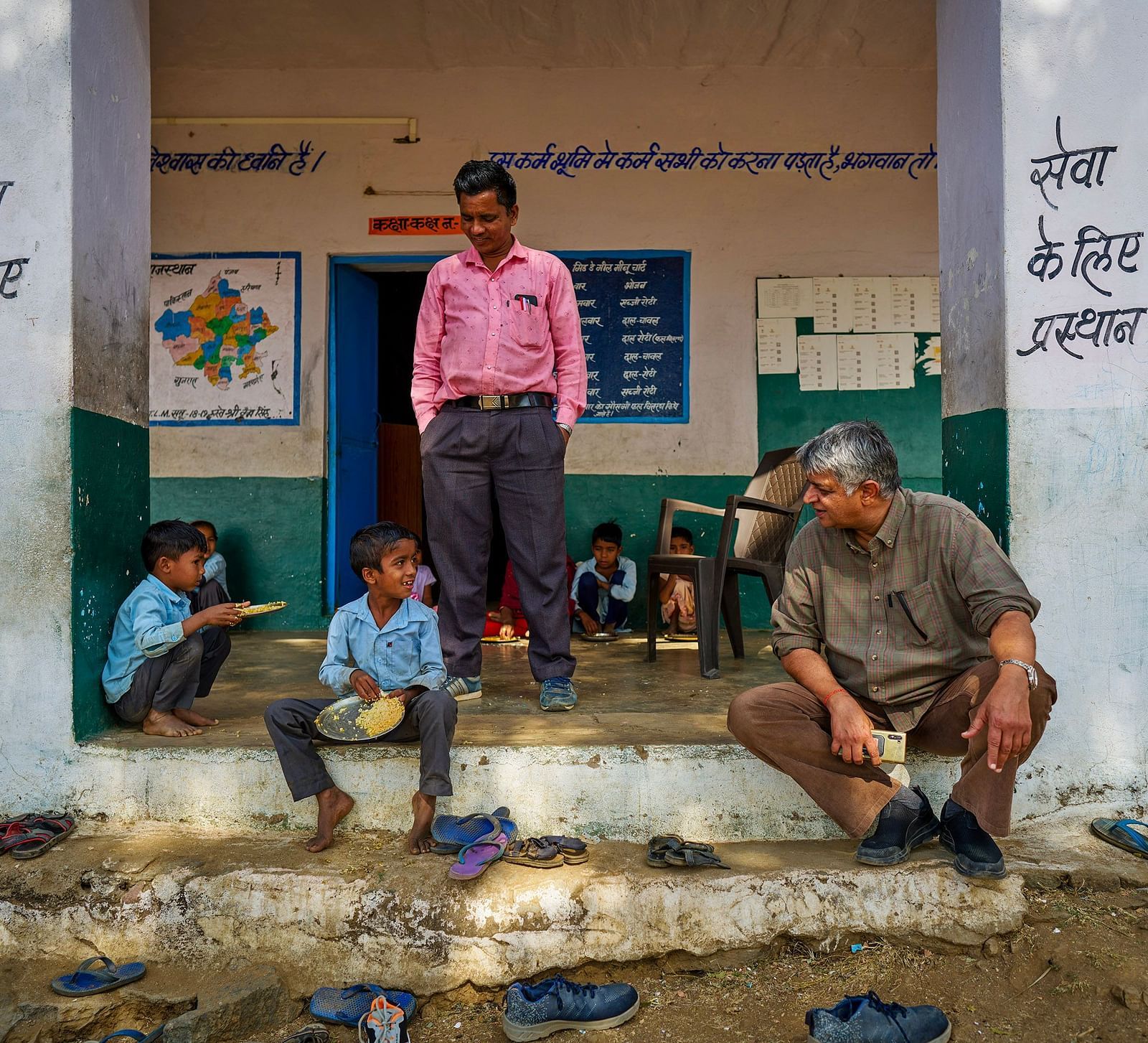 image of the old man sitting on the steps of the school with the children