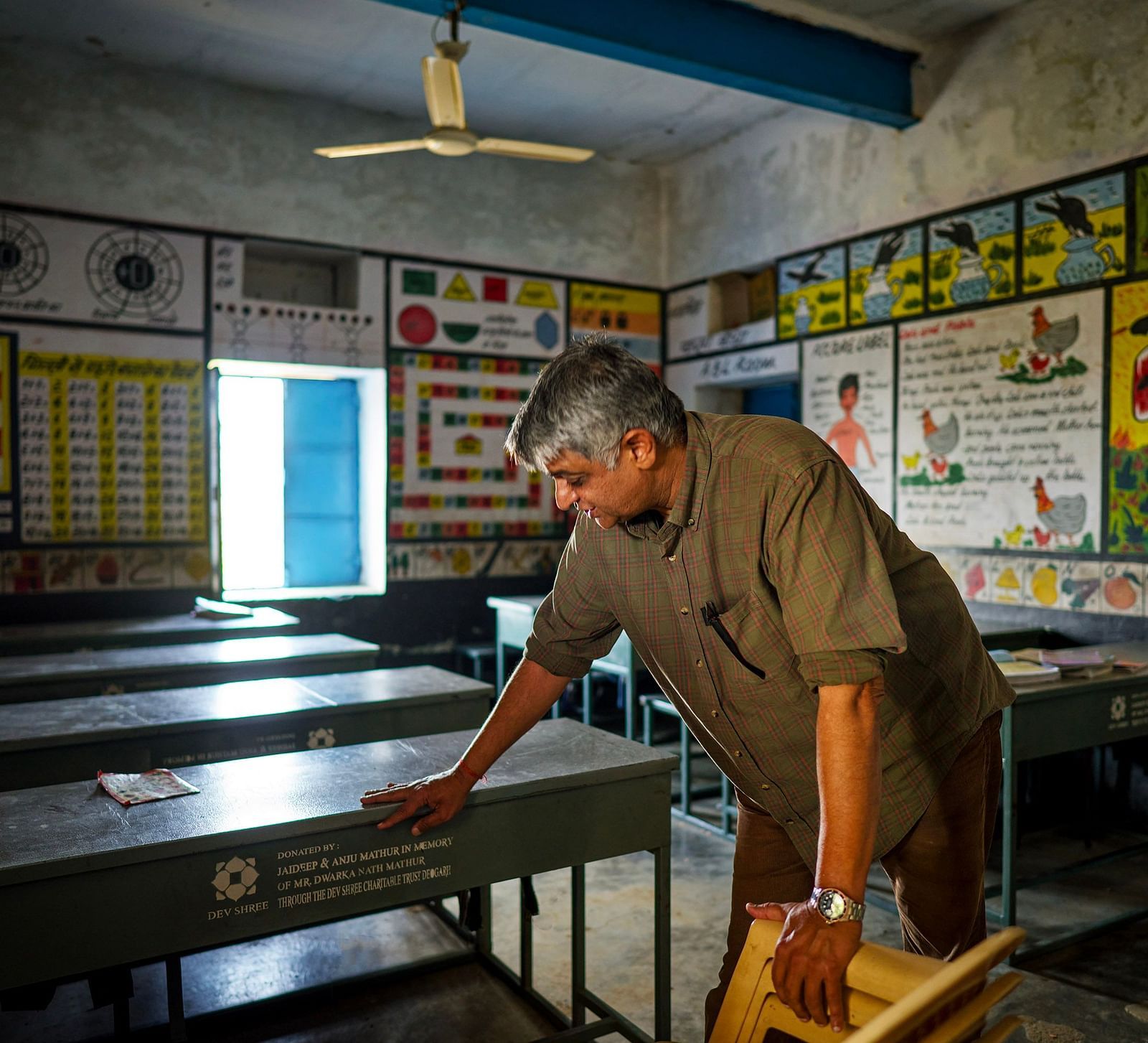 image of the old man cleaning an empty classroom with natural light coming from the window at the far end of the room