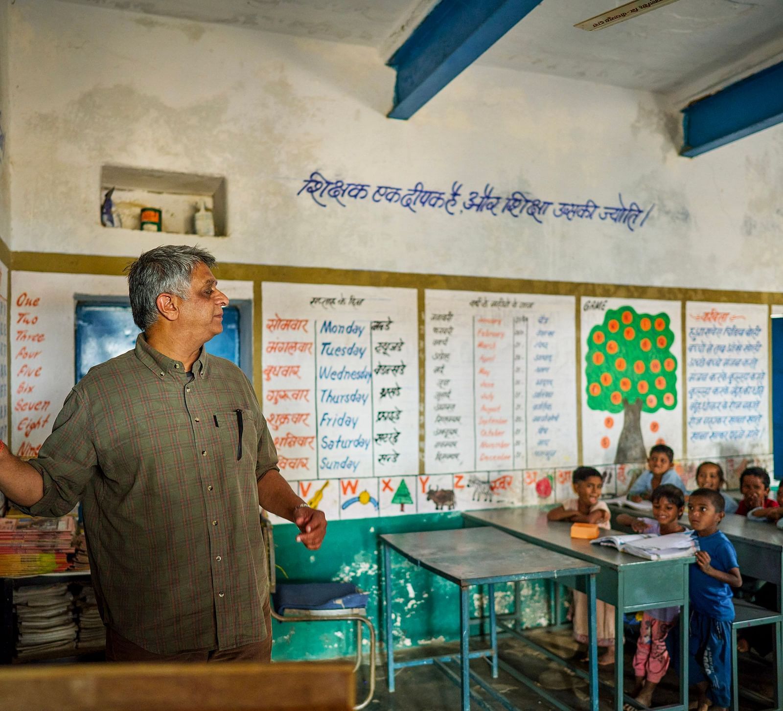 image of an old man teaching with the help of a chalk and blackboard to the students