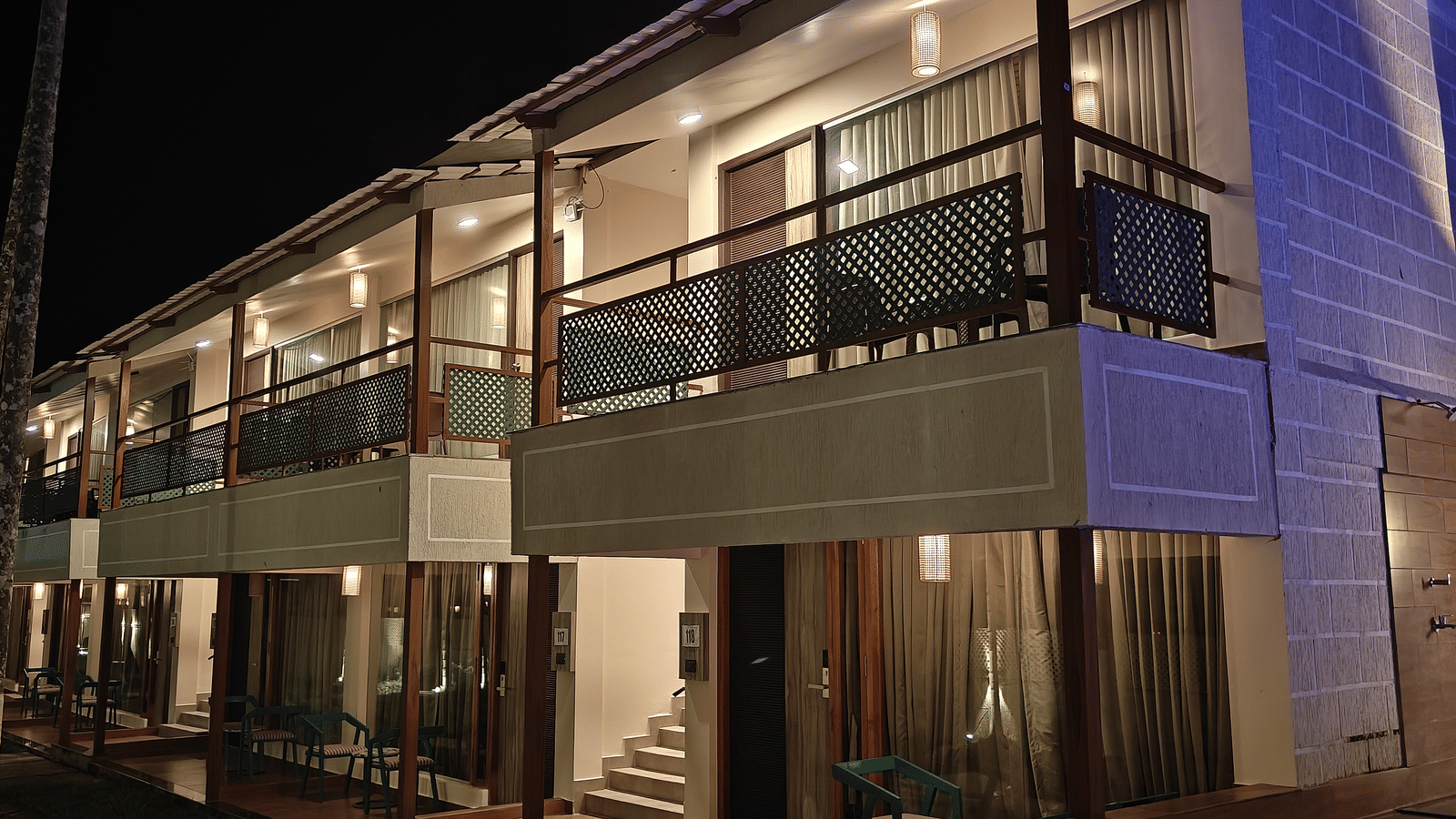 An exterior night view of Arina Island Resort showcasing two-story rooms with balconies and warm lighting