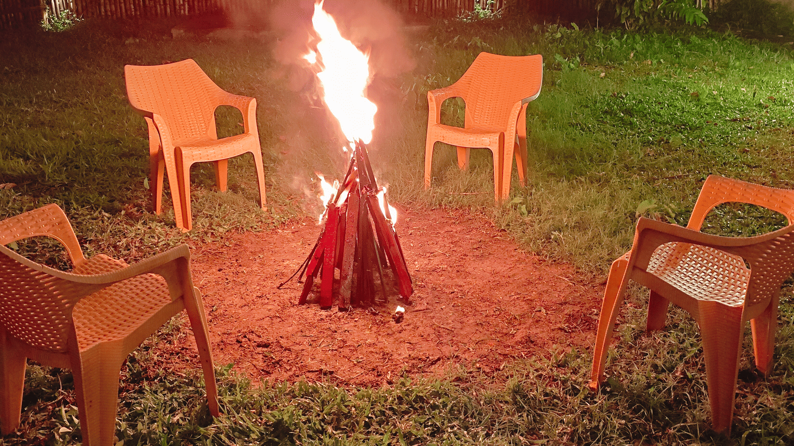 A bonfire setup at Arina Island Resort with chairs arranged around the fire on a grassy lawn