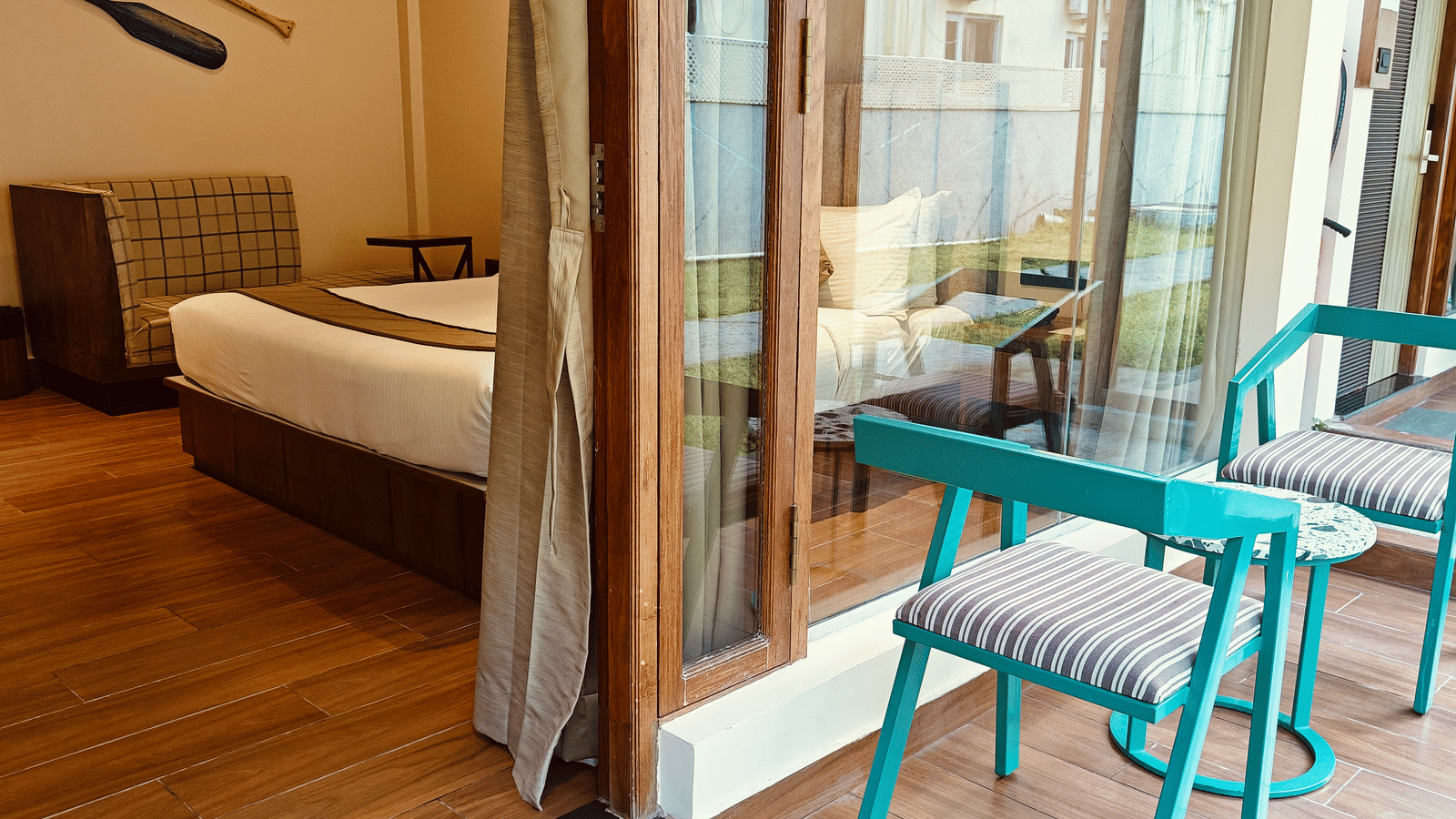 A bedroom at Red Skin Villa opening to a private sit-out area with patio chairs and glass doors