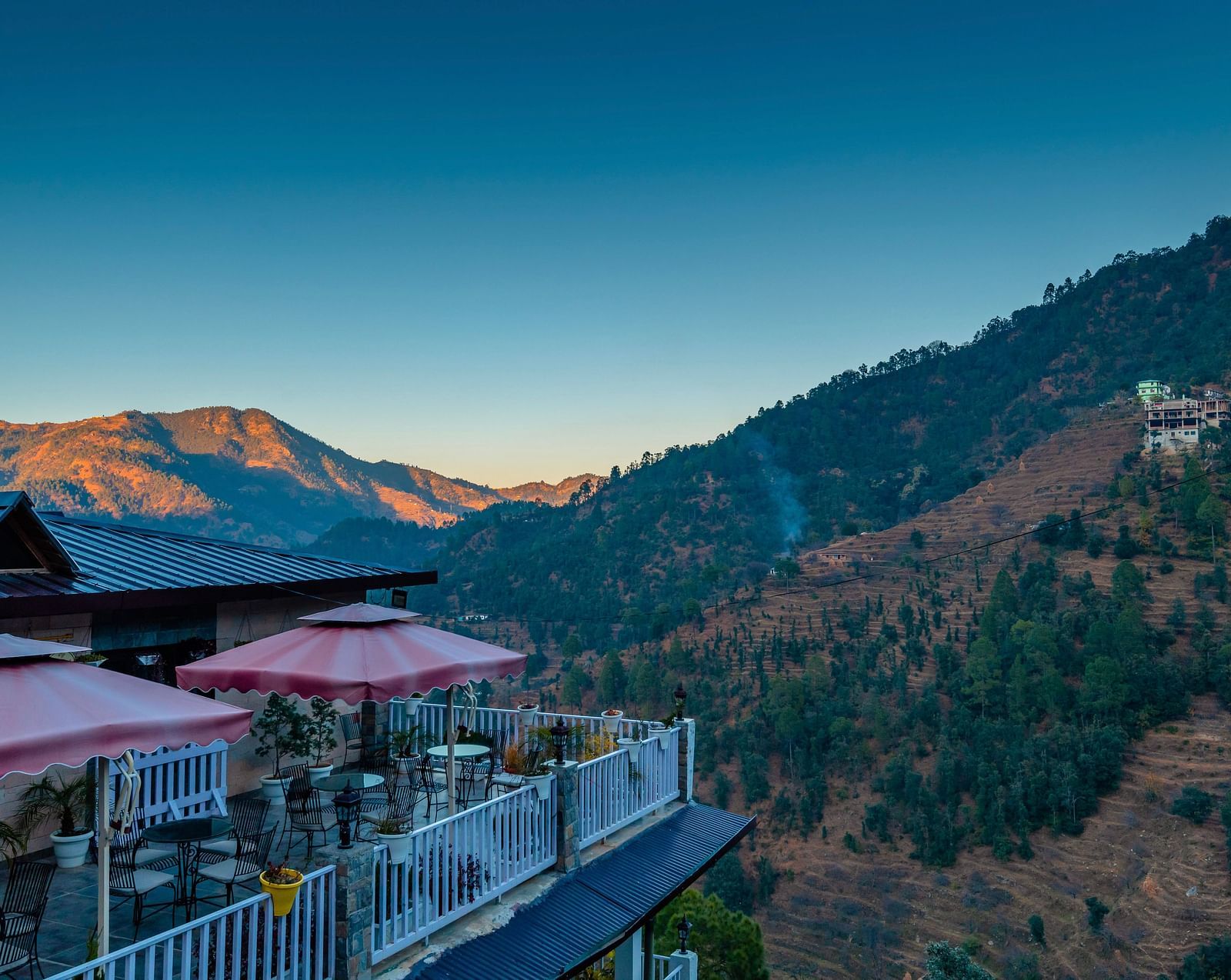 Balcony facade offering a mountain view with a sunset-colored sky and mountains.