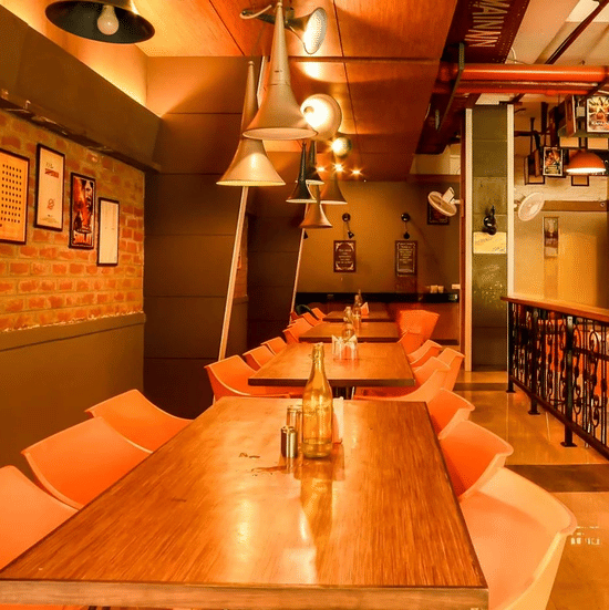 An image of a restaurant with several chairs and tables, ceiling lights hanging, photo frames on the walls, and other things - Hotel Polo Towers Group