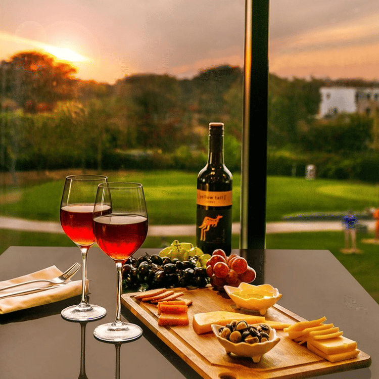 Two glasses of wine and a cheese board placed on a table - Karma Lakelands.