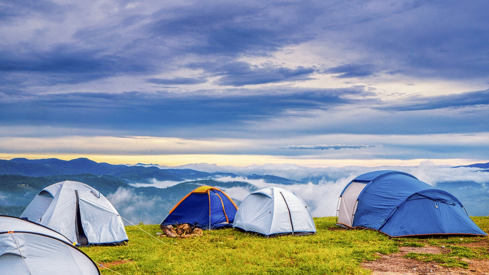 an image of dark clouds in the sky overlook the tents resting on the garden