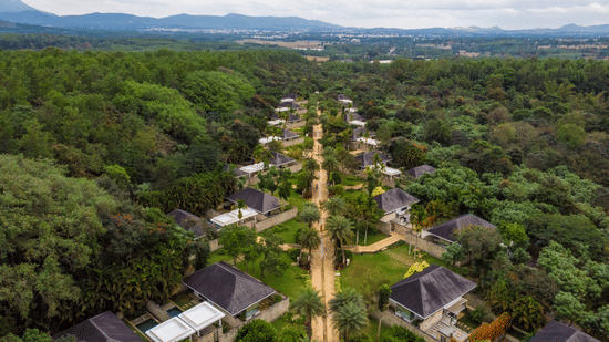Aerial view of The Serai Chikmagalur featuring the accommodations surrounded by lush greenery with a backdrop of mountains