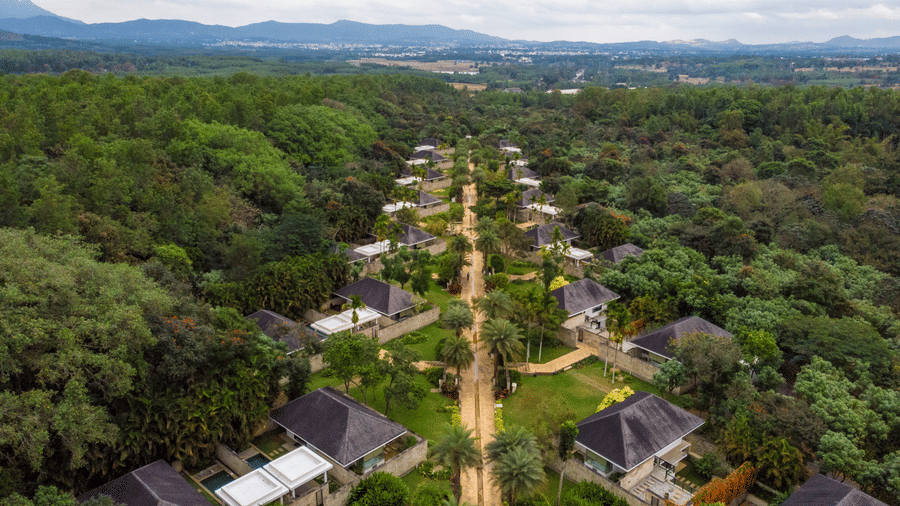 Aerial view of The Serai Chikmagalur featuring the accommodations surrounded by lush greenery with a backdrop of mountains