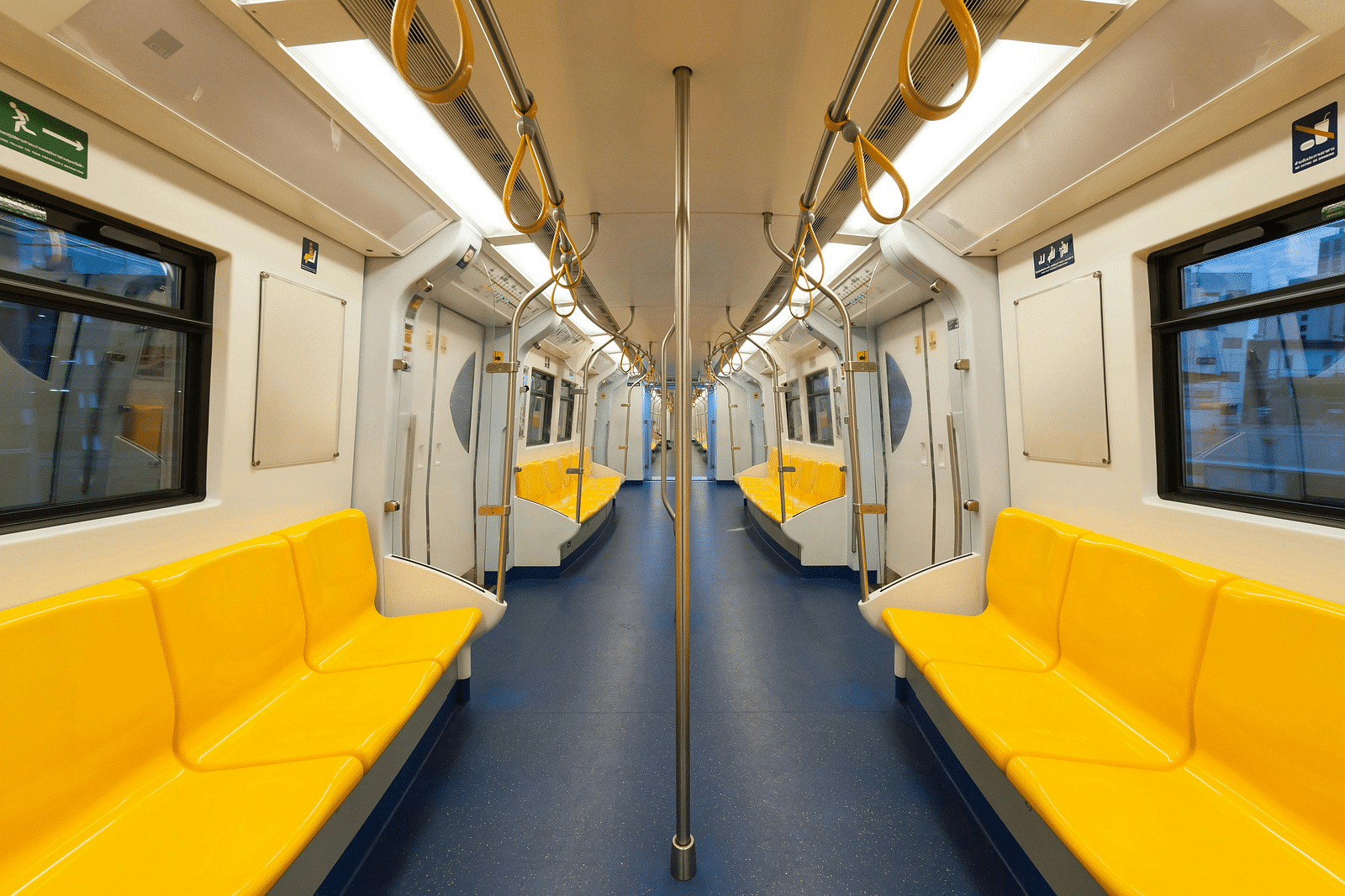 Interior of a well-lit metro with yellow seats. 