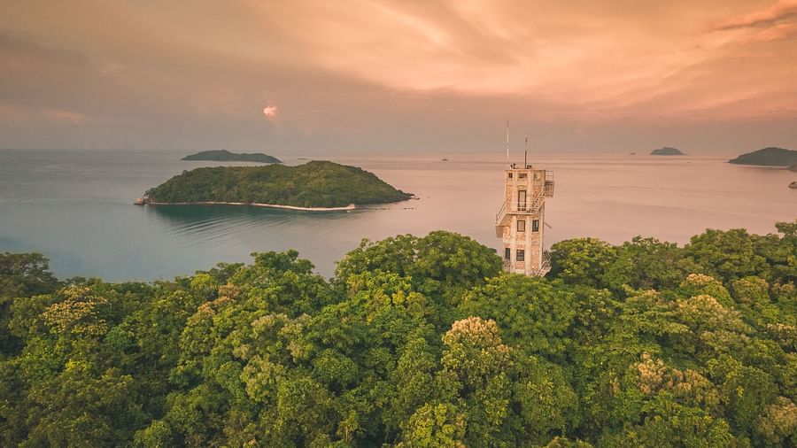 Aerial view of a green island with a white tower structure near Flower Island Resort.