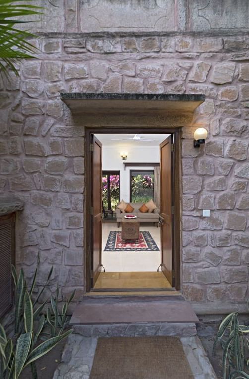An image of a wall with a wooden door leading to the MANVAR Resort & Desert Camp