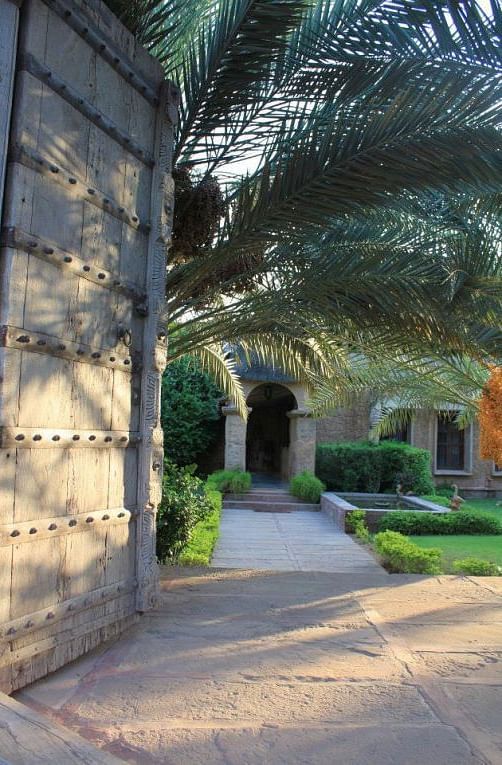 An image of a huge wooden gate which is the entry to MANVAR Resort & desert Camp with greenery around