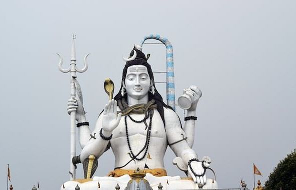 A statue of Shiva holds a trishul and damru, embodying strength and divine energy. The intricate details of the statue highlight Shiva's serene expression and powerful stance, symbolizing his role as the protector and transformer within Hindu mythology.