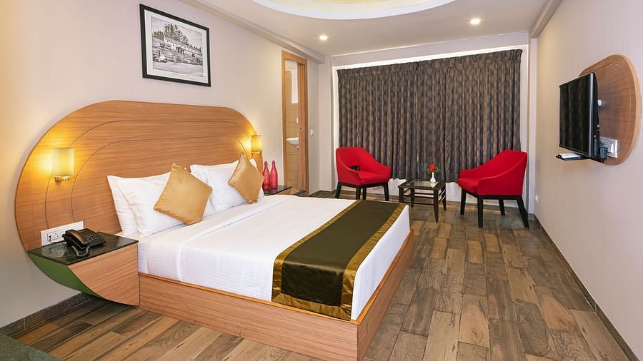 An image of a bedrom with dube sized bed and chairs on a different corner  | Mango HIll Central, Ooty