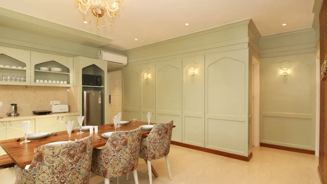 Hotel dining area with round table, floral chairs, and chandelier lighting