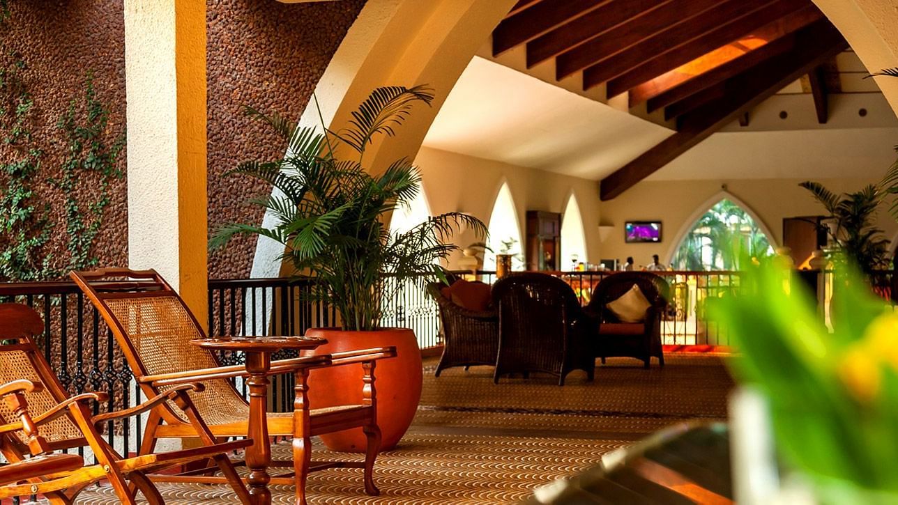overview of the lobby sit out area with wooden chairs and potted plants in view at Caravela Beach Resort.