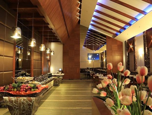 A beautifully decorated buffet counter with fresh flowers, soft lighting, and a luxurious dining ambience. - Dhanalakshmi Srinivasan Hotels, Perambalur
