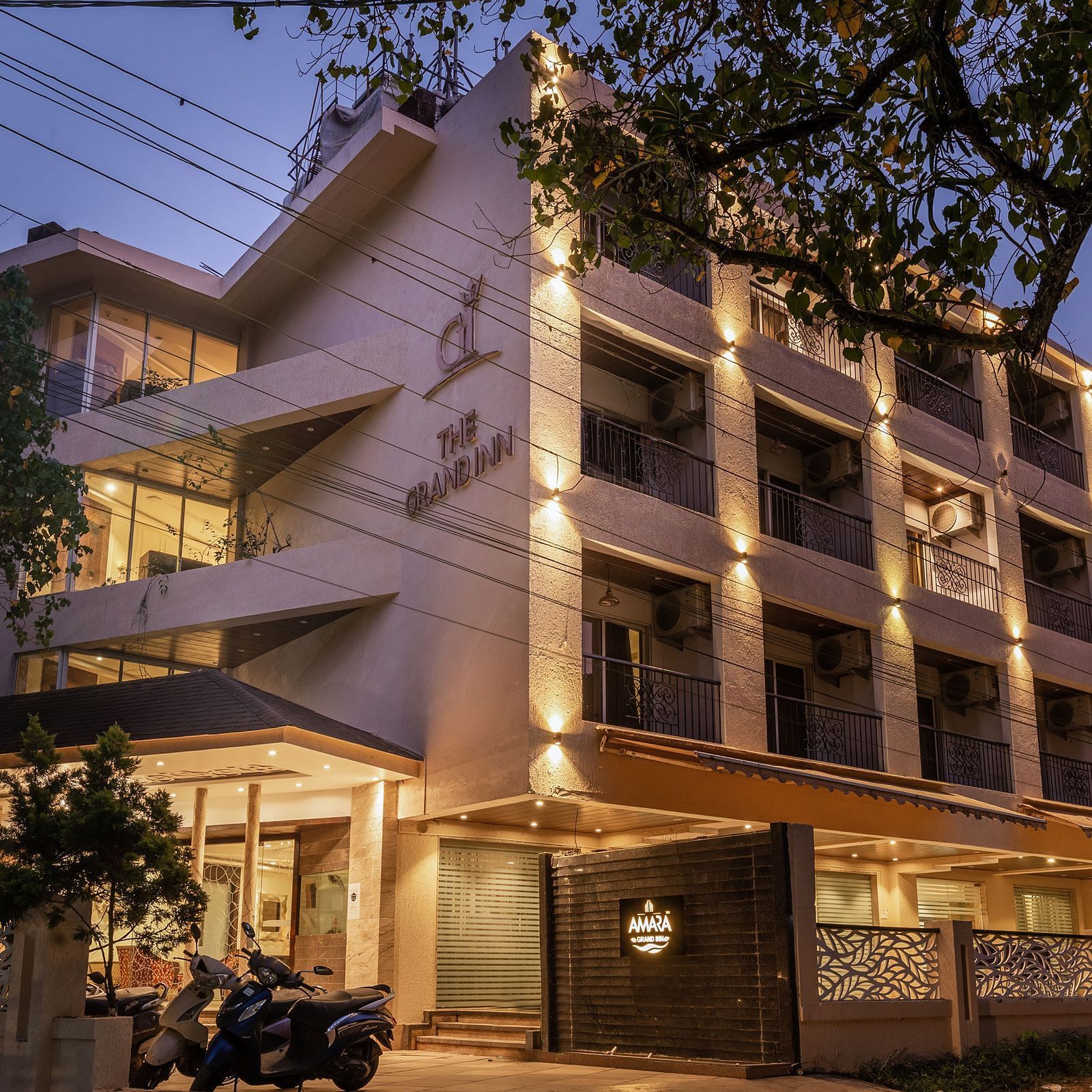 Night view facade of Calux Grand Inn, Calangute with trees on the side.