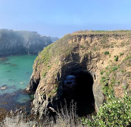 A huge arch in the middle of a mountain that leads to the ocean