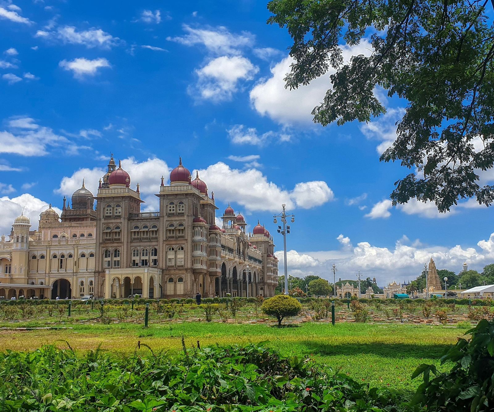 A far out view of the mysore palace with a manicured garden in the foreground
