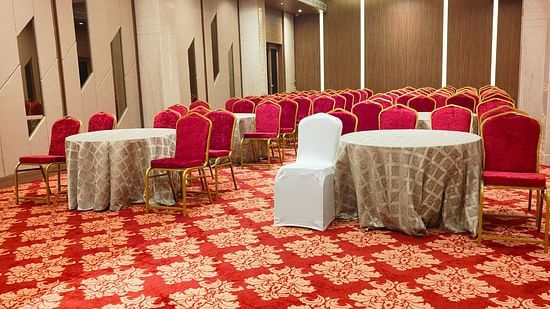 A banquet hall with chairs circled around the table facing  towards the stage The Orchid Hotel, Jamnagar. at 