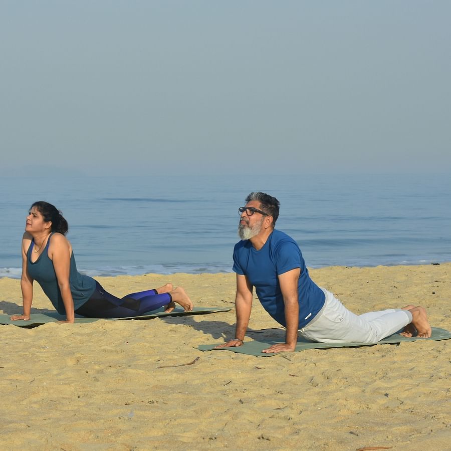 A couple performing Yoga on the beach with the sea in the background - Heritage Village Resort & Spa, Goa