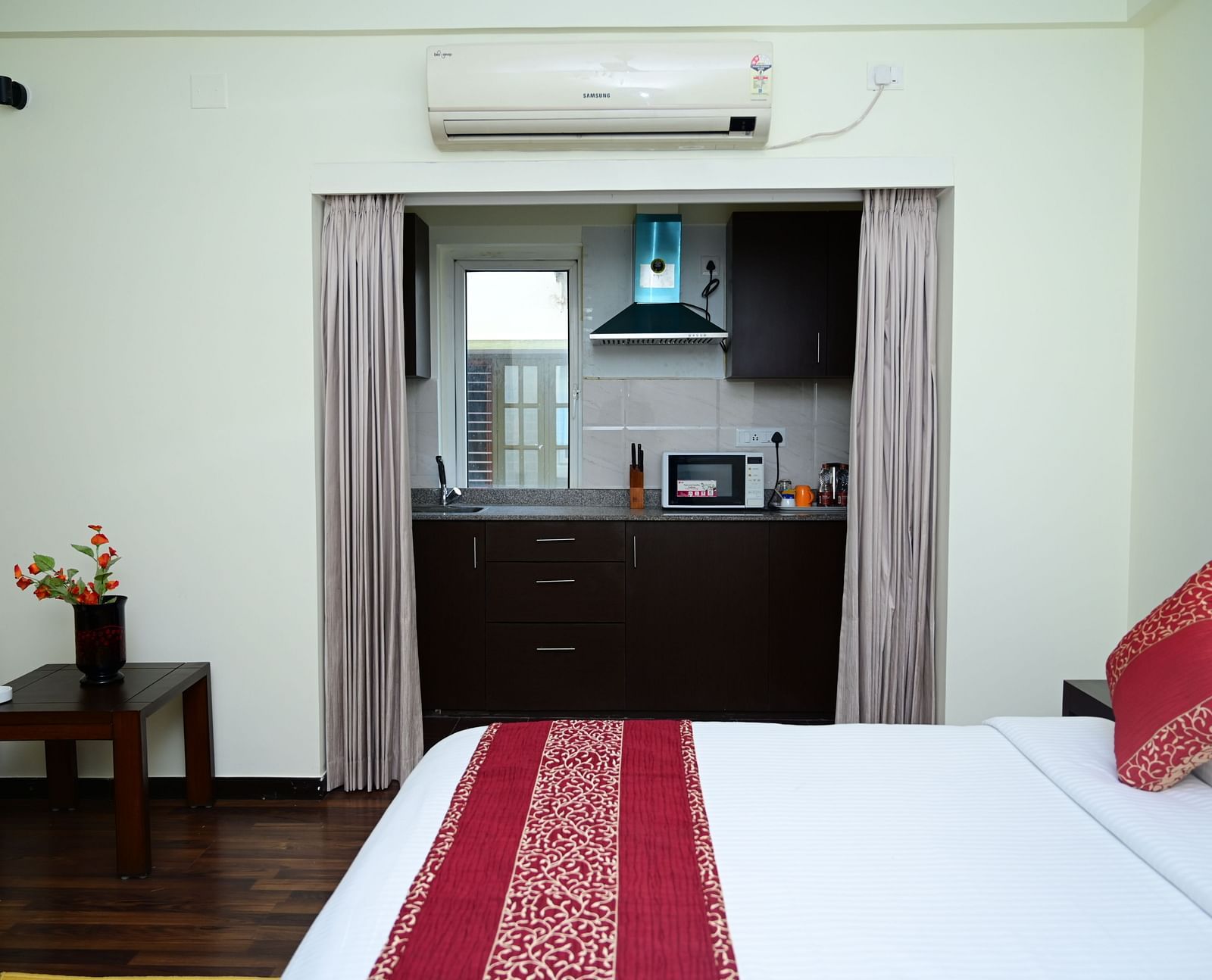 Image of a double bed with pink bedsheet and a kitchen visible from the Executive Suite at Sterling Keys by TGI