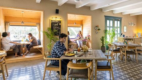 Poster of the 'Weekday Work-ation' featuring an image of a cafe with people working and the inclusions of the offer - Karma Chalets