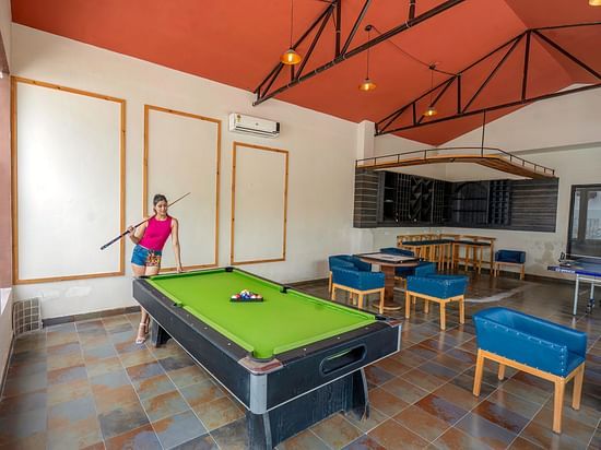 A lady standing beside the pool table, holding a cue stick.