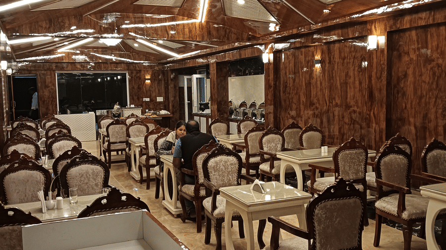 A well-lit multi-cuisine restaurant with wooden interiors and cosy dining setup for guests - Benzz Park, Kodaikanal