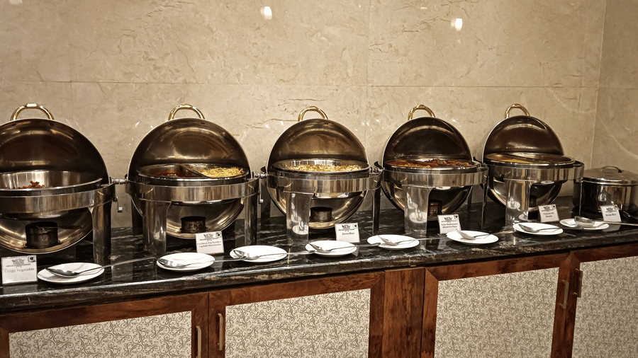 A buffet counter with gleaming chafing dishes arranged for a delectable multi-cuisine dining spread - Benzz Park, Kodaikanal