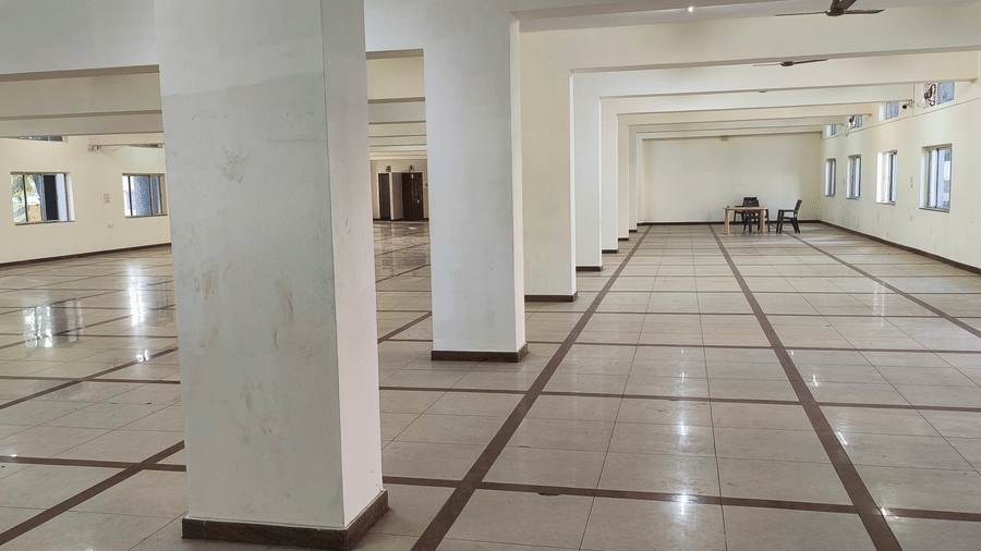 A spacious, empty ballroom or convention hall with polished tile flooring and multiple support pillars, ready for events at BNGV Grandeur Hotel and Banquets.