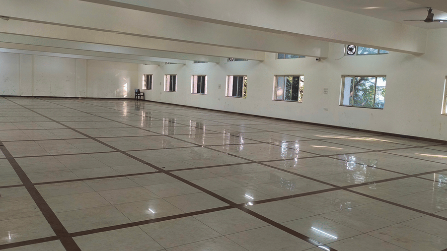 A wide perspective of a spacious, empty hall at BNGV Grandeur Hotel and Banquets, featuring numerous windows along the walls.