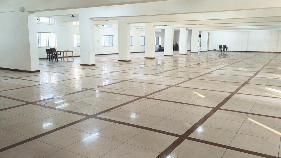 A long view of an expansive, empty hall at BNGV Grandeur Hotel and Banquets, revealing rows of pillars and a polished floor.