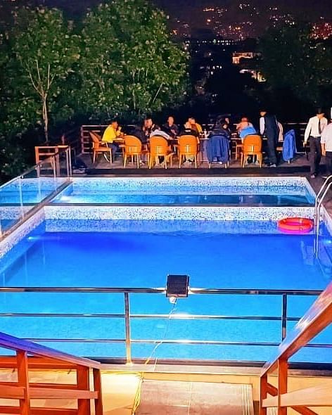 Dining setup for a large group on the patio of the illuminated swimming pool at Mandala Norling Lords Prime, Kathmandu.